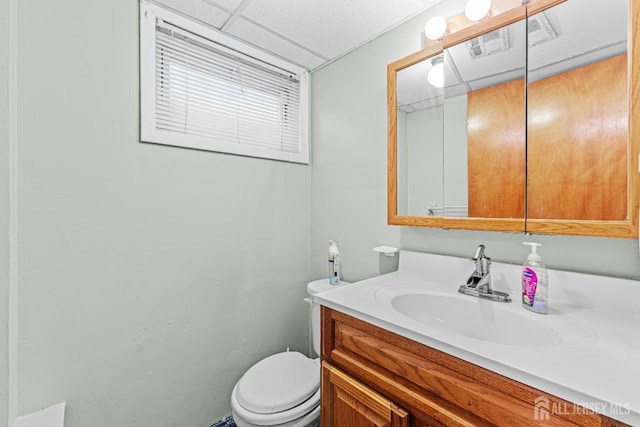 bathroom featuring vanity, a drop ceiling, and toilet