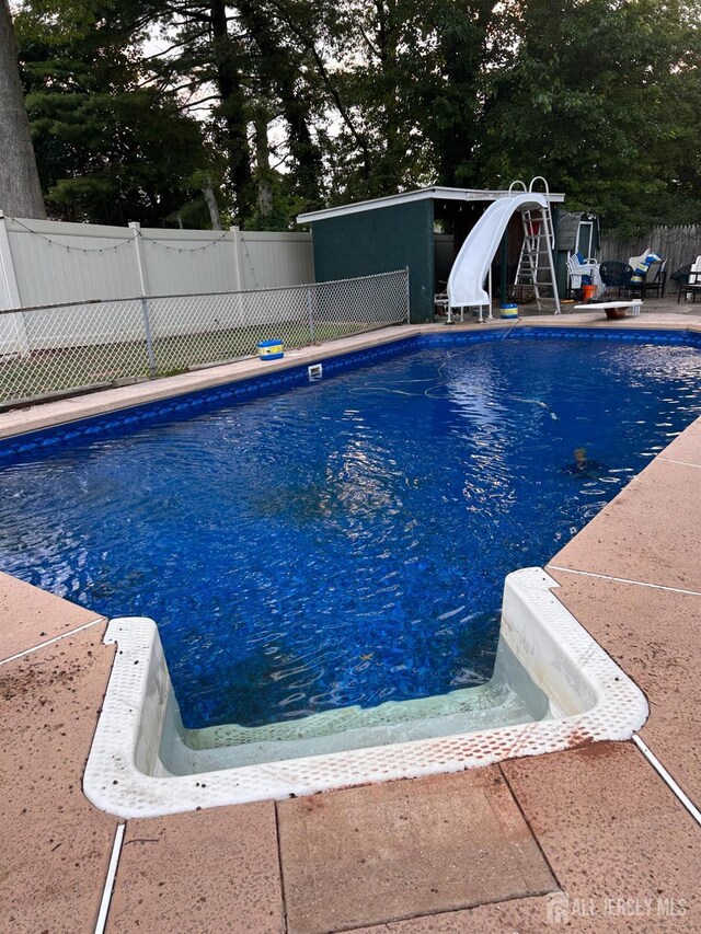 view of swimming pool with fence, a water slide, a patio, and a fenced in pool