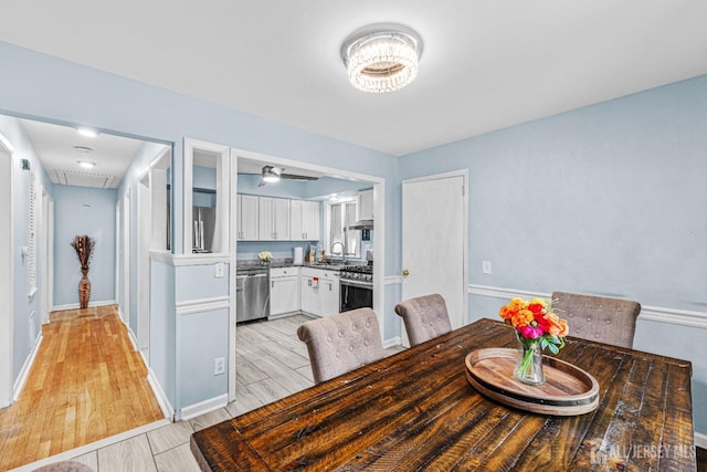 dining area with light wood-type flooring, attic access, and baseboards