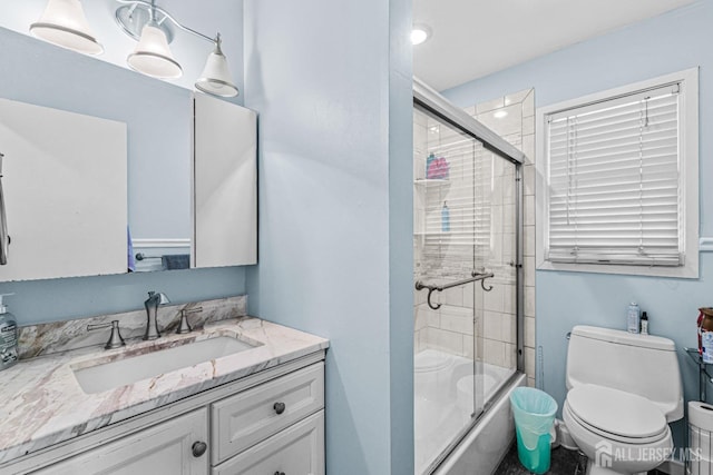 full bathroom with toilet, combined bath / shower with glass door, and vanity