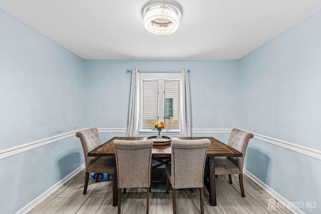 dining space with an inviting chandelier, baseboards, and light wood finished floors
