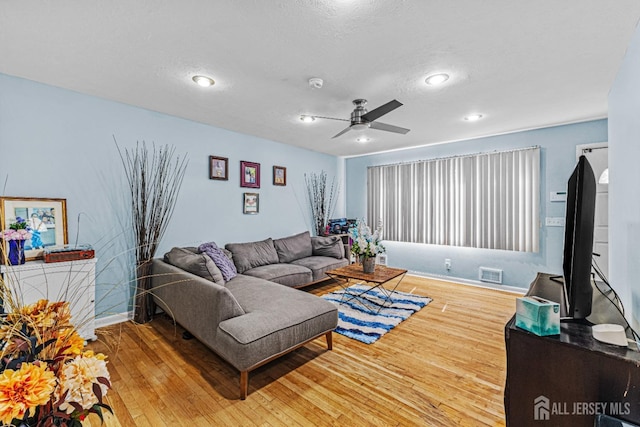 living area featuring ceiling fan, a textured ceiling, baseboards, visible vents, and hardwood / wood-style flooring