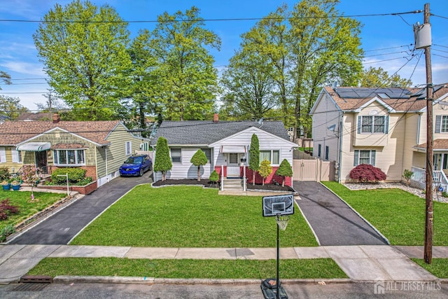 bungalow-style house featuring fence, driveway, a gate, and a front lawn