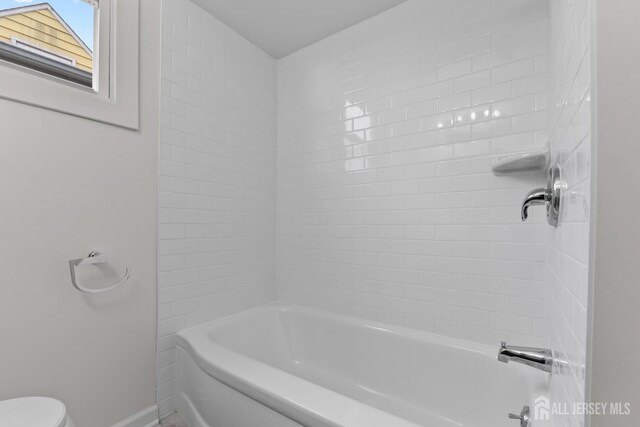 bathroom featuring toilet and bathing tub / shower combination