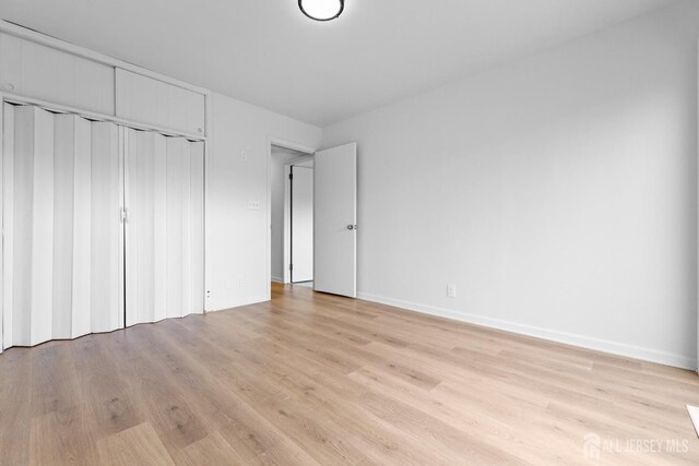 unfurnished bedroom with light hardwood / wood-style flooring and a closet