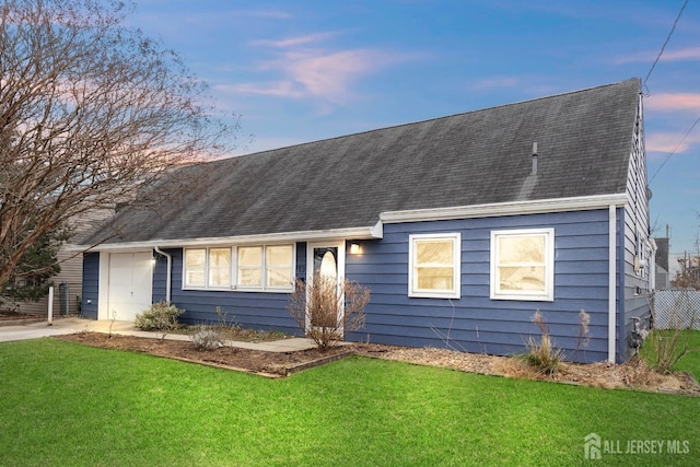 view of front of home with a lawn, an attached garage, driveway, and a shingled roof