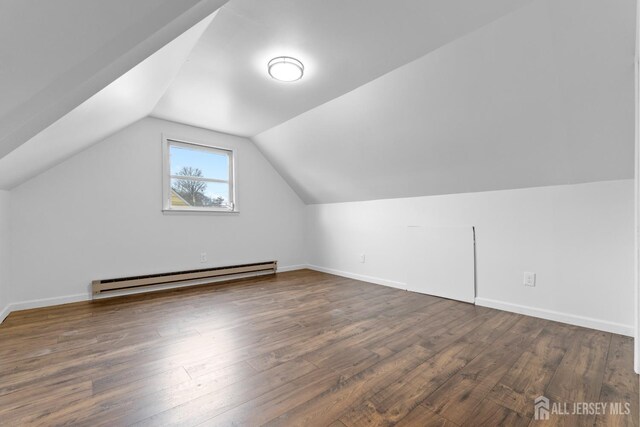 additional living space featuring baseboard heating, dark wood-type flooring, and vaulted ceiling