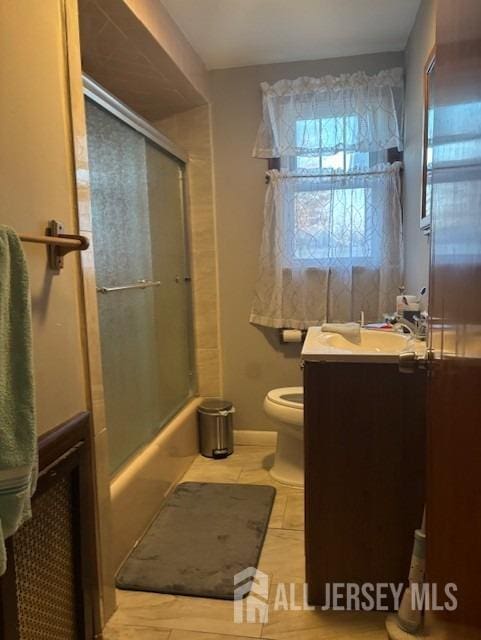 full bathroom featuring toilet, vanity, tile patterned floors, and enclosed tub / shower combo