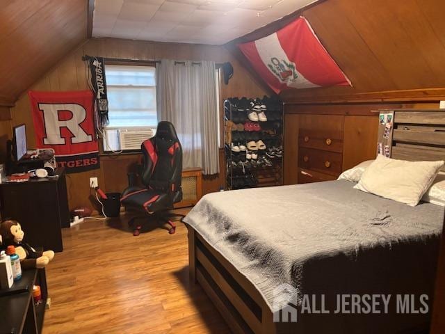 bedroom featuring wooden walls, cooling unit, lofted ceiling, and wood finished floors