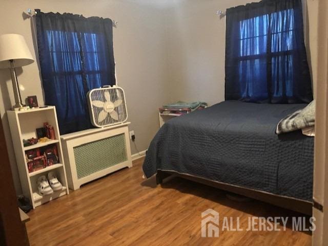 bedroom featuring wood-type flooring and radiator heating unit