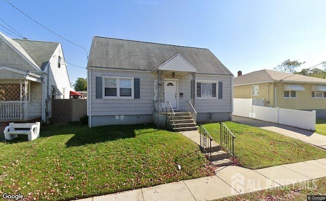 bungalow with roof with shingles, a front yard, and fence