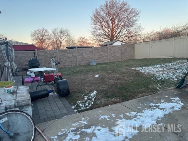 yard at dusk with a patio area and a fenced backyard