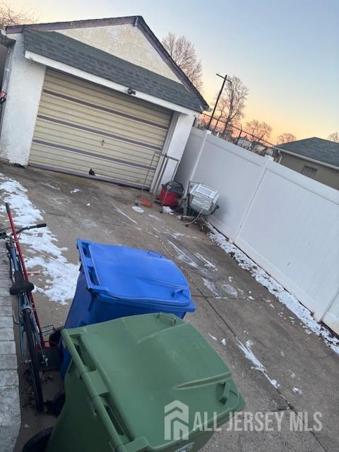 garage at dusk featuring fence