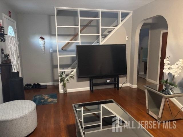 living room with baseboards, arched walkways, and wood finished floors