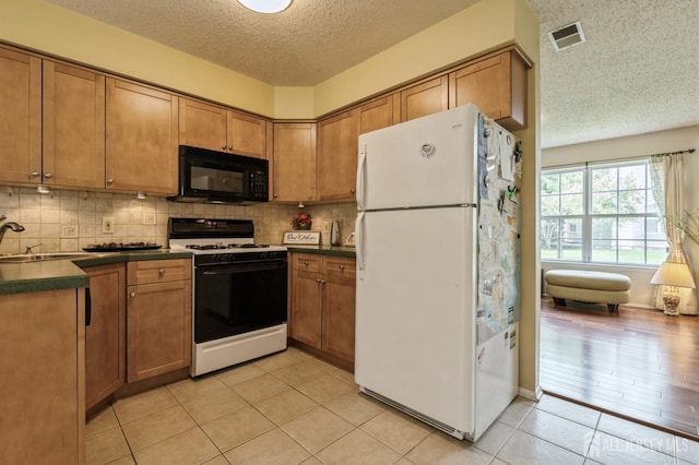 349 Lunar Rd, Piscataway, NJ 08854 - kitchen featuring freestanding refrigerator, gas range, black microwave, a textured ceiling, and brown cabinets