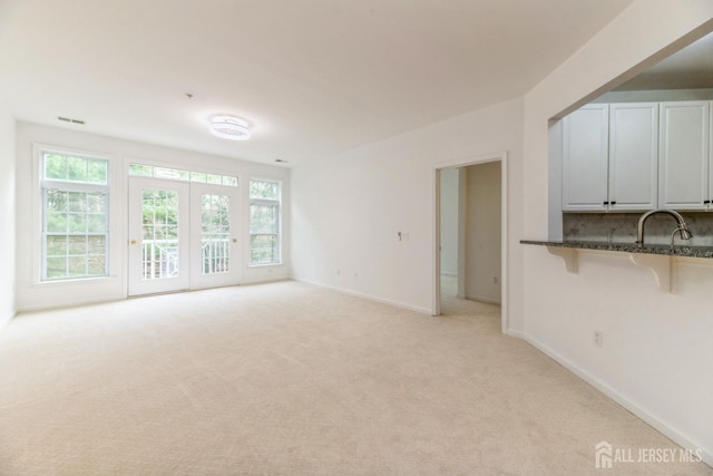 1109 Cedar Village Blvd, East Brunswick, NJ 08816 - unfurnished living room featuring light carpet, healthy amount of natural light, baseboards, and a sink