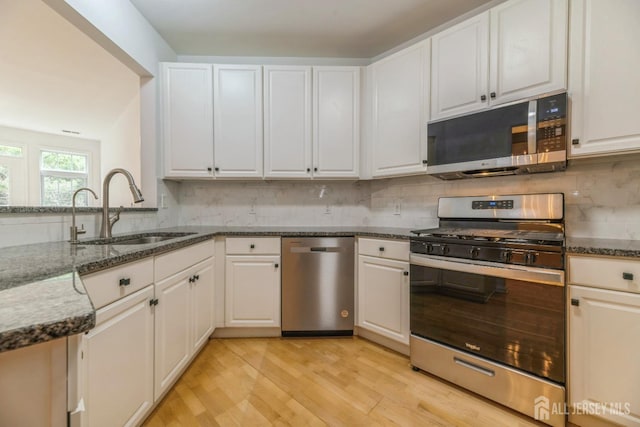 1109 Cedar Village Blvd, East Brunswick, NJ 08816 - kitchen with stainless steel appliances, a sink, light wood-style floors, dark stone countertops, and decorative backsplash