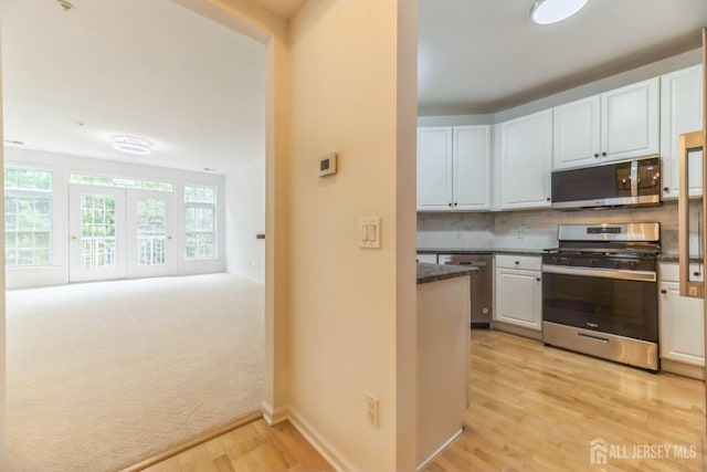 1109 Cedar Village Blvd, East Brunswick, NJ 08816 - kitchen featuring stainless steel appliances, dark countertops, light wood-style flooring, white cabinets, and tasteful backsplash