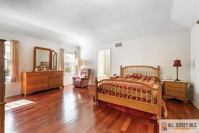 bedroom featuring a textured ceiling, visible vents, and wood finished floors