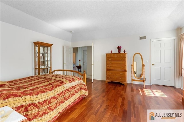 bedroom featuring a textured ceiling, visible vents, and wood finished floors