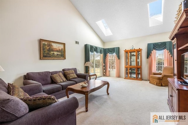 living area with light colored carpet, visible vents, a skylight, and high vaulted ceiling