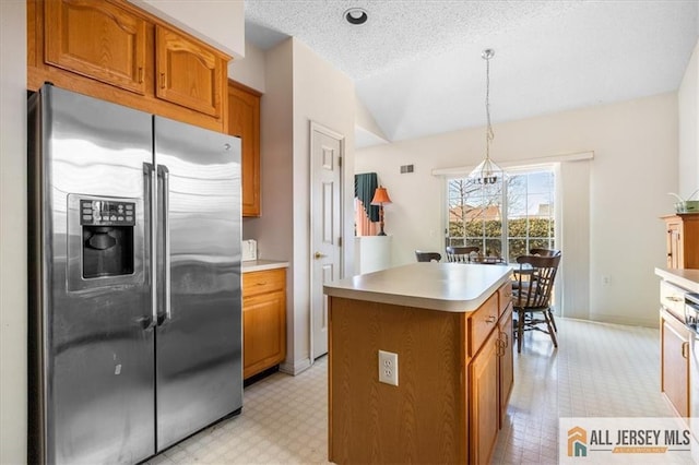 kitchen with light floors, brown cabinets, stainless steel refrigerator with ice dispenser, and vaulted ceiling