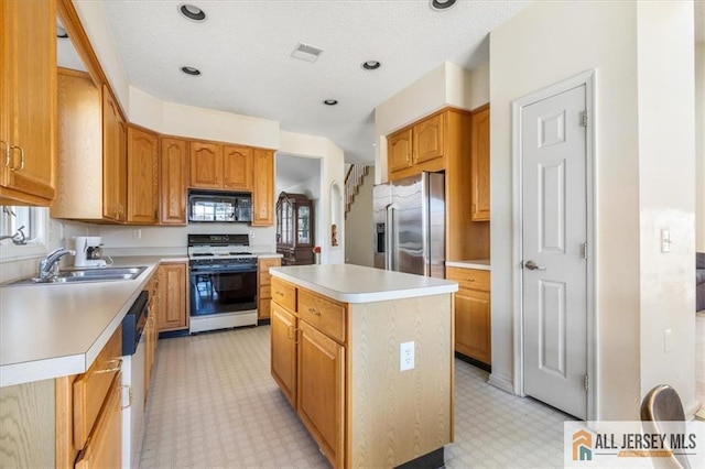 kitchen with visible vents, a sink, a kitchen island, light countertops, and appliances with stainless steel finishes
