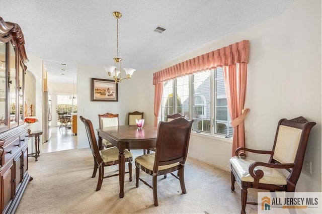 dining room featuring light carpet, a notable chandelier, and visible vents