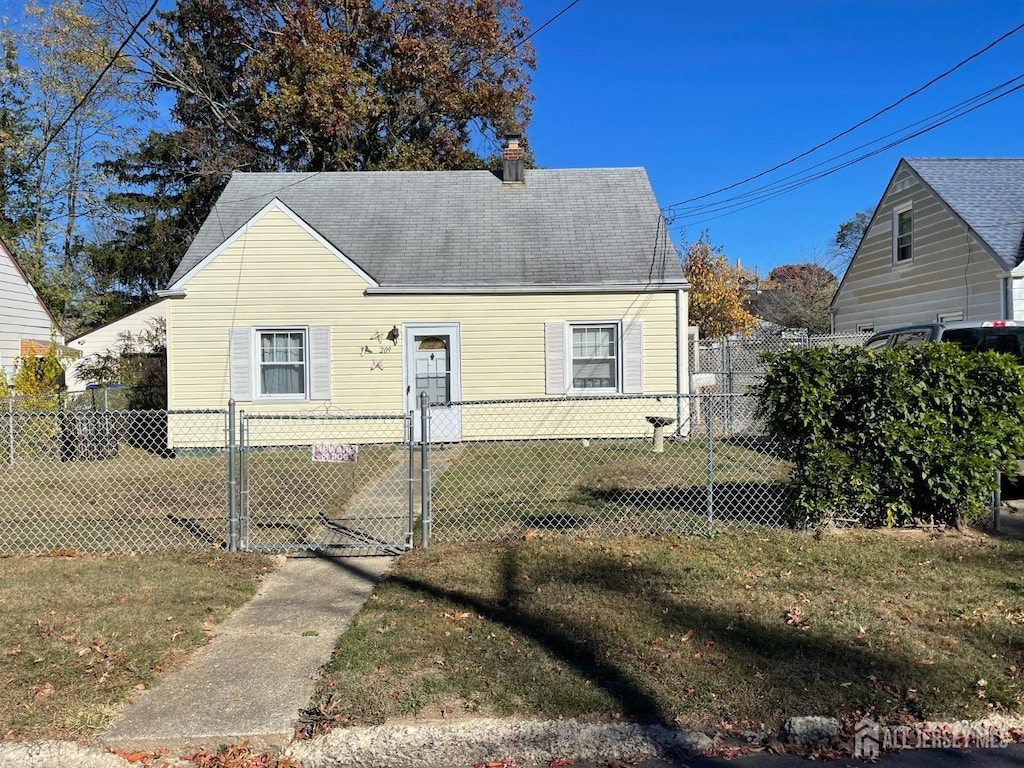 cape cod-style house with fence private yard, a gate, roof with shingles, and a front lawn