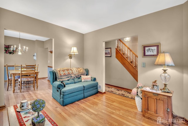 living area featuring a chandelier, stairs, baseboards, wood finished floors, and visible vents