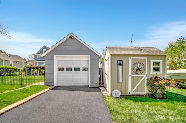 detached garage featuring fence and aphalt driveway