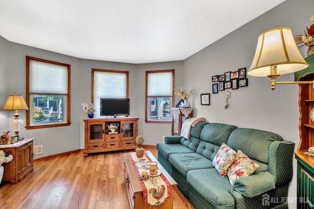 living room featuring visible vents, light wood-style flooring, and baseboards