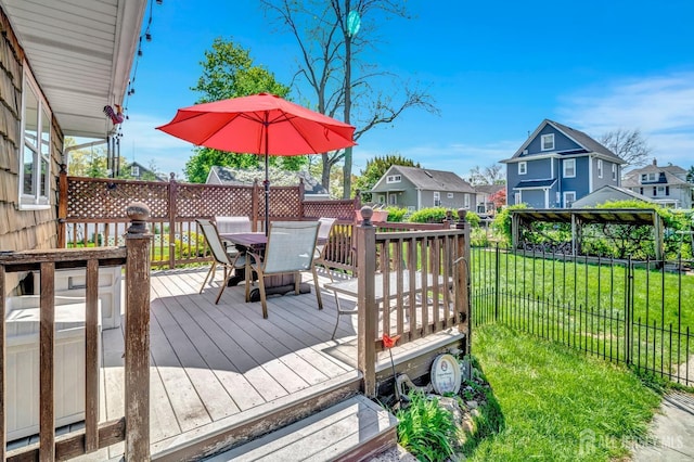 wooden terrace featuring outdoor dining area, a lawn, fence, and a residential view