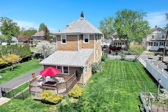 back of house featuring a yard, a wooden deck, a fenced backyard, and roof with shingles
