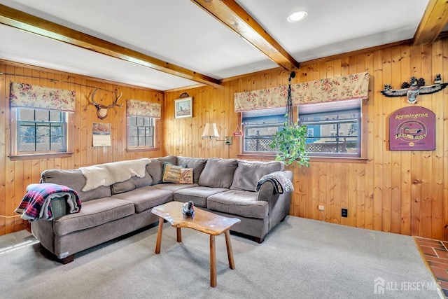carpeted living room featuring beamed ceiling and wood walls