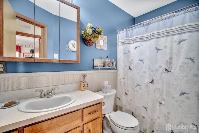 bathroom with vanity, wainscoting, curtained shower, and toilet