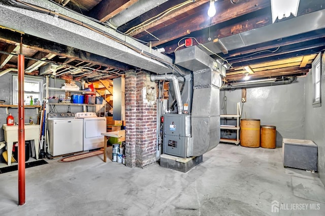basement with heating unit, separate washer and dryer, and a sink