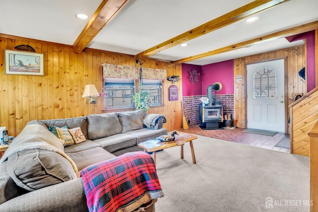 living area with wooden walls, beamed ceiling, a wood stove, and recessed lighting