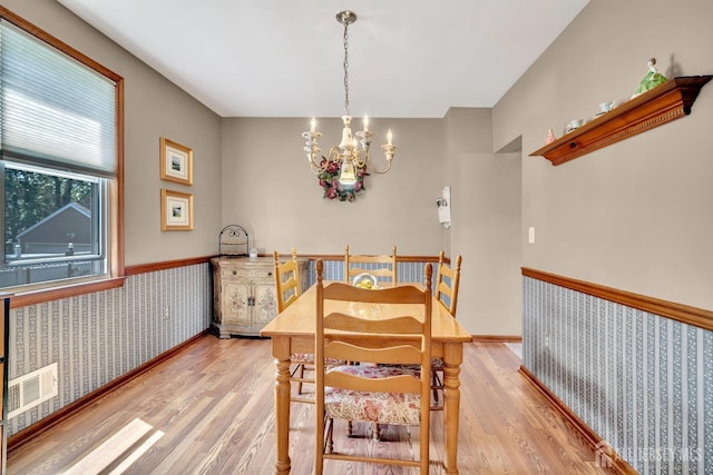 dining area featuring visible vents, light wood-style flooring, wainscoting, and a chandelier