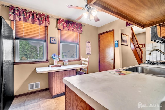 kitchen with ceiling fan, a sink, freestanding refrigerator, baseboards, and visible vents
