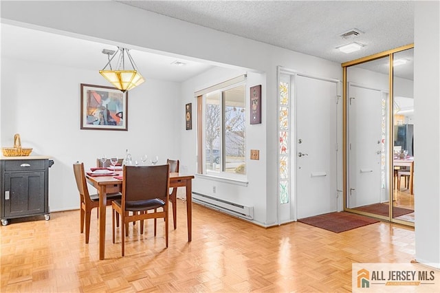 dining room with visible vents, baseboard heating, and a textured ceiling