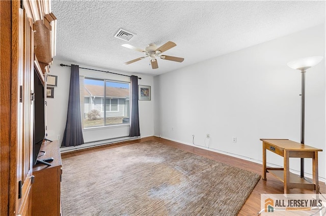 unfurnished room with visible vents, baseboards, wood finished floors, a textured ceiling, and a ceiling fan