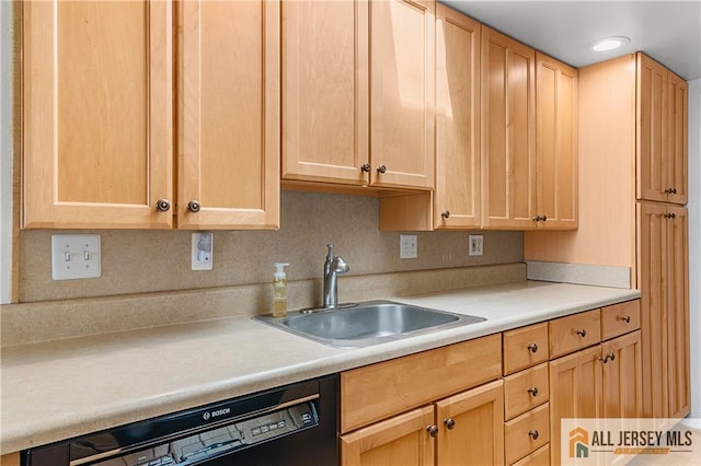 kitchen featuring light countertops, black dishwasher, light brown cabinetry, and a sink