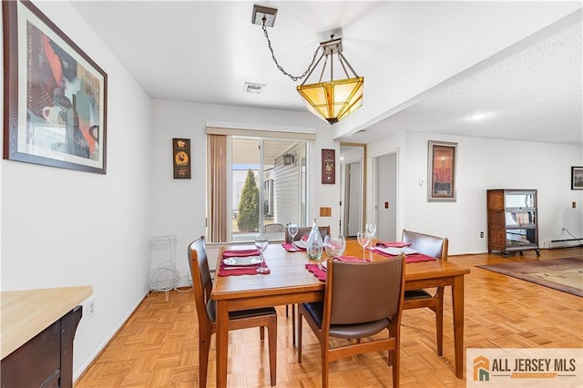 dining space featuring visible vents, a textured ceiling, and a baseboard heating unit