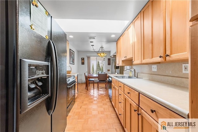 kitchen featuring visible vents, black appliances, light brown cabinetry, a sink, and light countertops