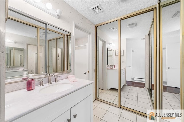 bathroom featuring visible vents, vanity, tile patterned floors, a textured ceiling, and a baseboard radiator