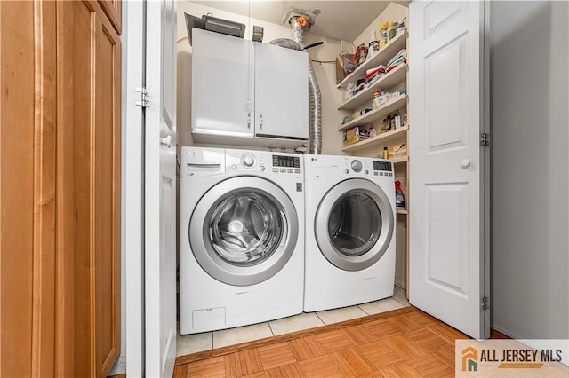 washroom featuring light tile patterned floors, cabinet space, and washing machine and clothes dryer