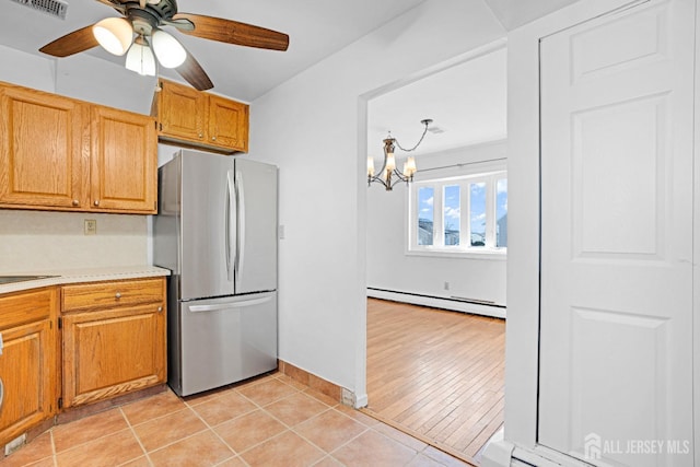 kitchen featuring stainless steel fridge, sink, light tile patterned floors, a baseboard radiator, and ceiling fan with notable chandelier