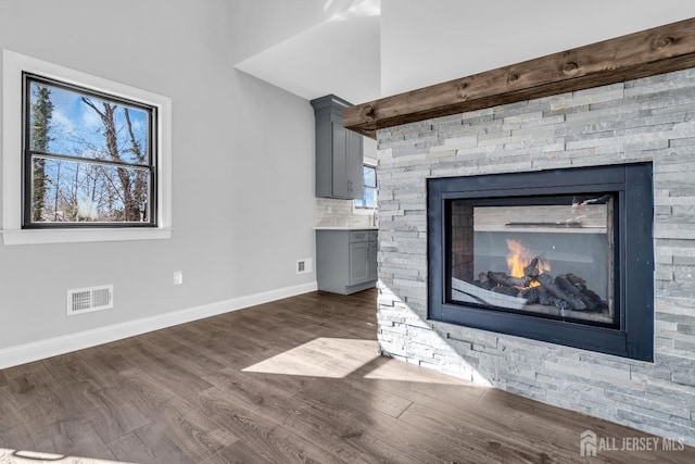 room details featuring a fireplace, tasteful backsplash, visible vents, wood finished floors, and baseboards