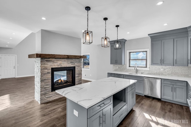 kitchen featuring light stone counters, gray cabinetry, a kitchen island, dishwasher, and pendant lighting